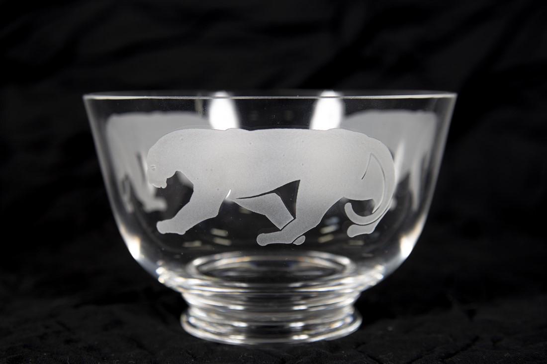 Cartier, Glass Panthere Bowl: Cartier. Glass. Height: 3 3/4", Diameter: 5 3/4". Cartier Panthere glass bowl. Footed glass bowl featuring three etched panthers around the sides of the bowl. Etched signature Cartier to the underside