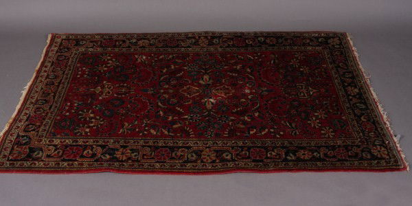 Sarouk Rug, Iranian, 20th Century, Red Field with: Red field with overall blue, sand and brown foliate motif. Within a black foliate border. Dimensions: 5' 1" x 4' 5". Condition: One end with brown stains. The end borders are fringed.
