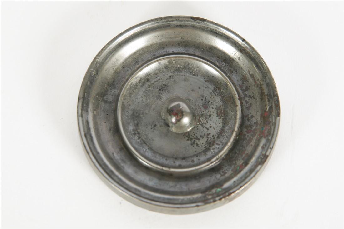 Silver Metal Disc Mirror: Metal. Height: 1/2", Diameter: 3 1/2" Heavy, silver-colored metal disc with concentric circle pattern. Raised center element with bead-like hole. Reverse is polished to a mirror-like surface.