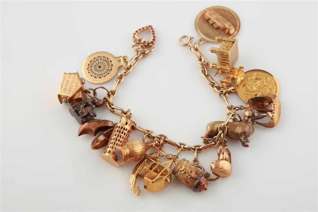 14k Lady's Charm Bracelet with 17 Charms: 14k yellow gold lady's charm bracelet. Piece is made up with 17 three-dimensional charms, all made of 18k, 14k, or 9k yellow gold. Bracelet weighs 72g. Charms consist of: a heart, Notre Dame de Paris