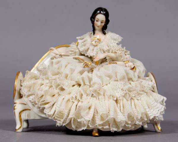Porcelain Crinoline Maiden Seated on A Settee: Porcelain crinoline figure. Continental, 20th century. A maiden seated on a settee. Height 5", length 5 1/2". Condition: With damage to the crinoline.