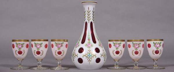 Bohemian Cranberry White Cased Glass Decanter, 20th C.: Bohemian cranberry white cased glass and enameled decanter and six cordial glasses. German, 20th century. Decanter height 10", glasses height 4". Condition: One cordial glass is cracked and glued thro