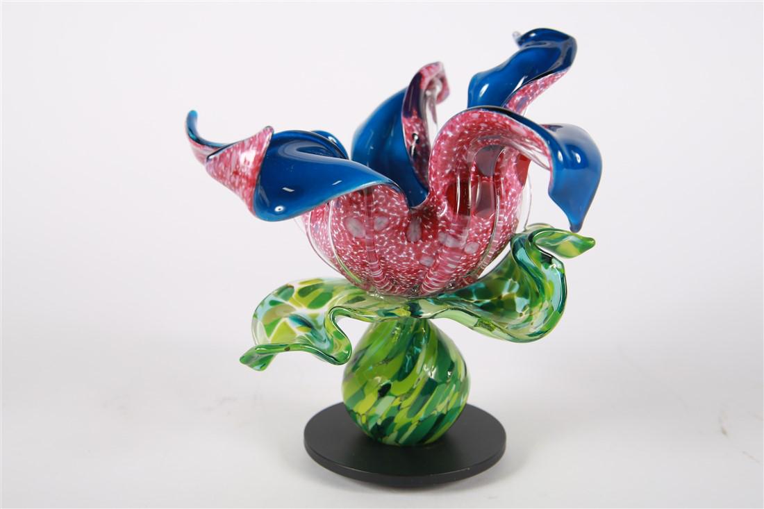 April Wagner, Art Glass Carnivorous Flower: April Wagner (American). Glass, metal base, 2018. Epiphany Studios. Height: 7 1/4", Length: 7", Depth: 8". Pink speckled glass flower sculpture with blue interior and green speckled leaves by Pontiac,