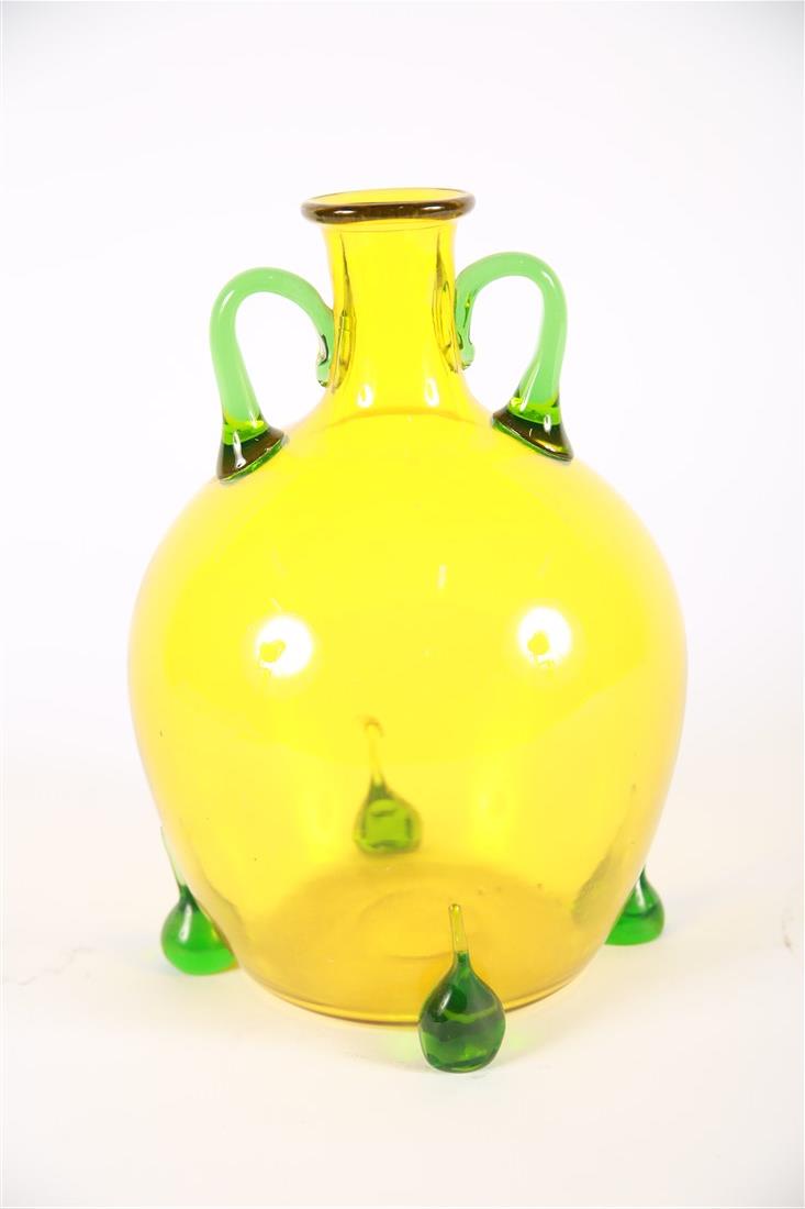 Yellow Lemon Bottle Vase with Green Handles: Glass. Height: 10 1/4", Diameter: 6". Clear yellow and green glass. Wide round form. Narrow neck. No markings.
