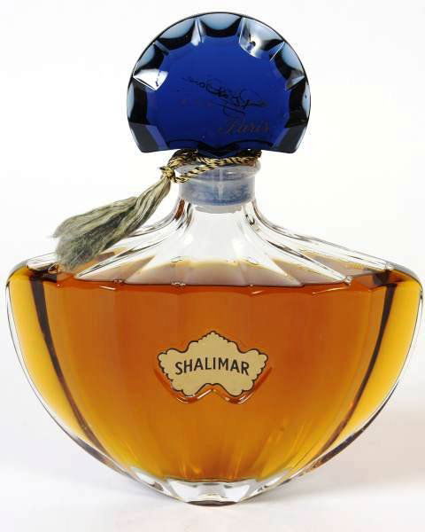Guerlain Factice "Shalimar" Perfume Bottle, Signed: Factice "Shalimar" perfume display bottle made by Guerlain. Paris, France, 20th century. With blue glass cap and having cord ribbon around neck. Signed on cap. Height 13", width 10 1/2", depth 3 1/2".