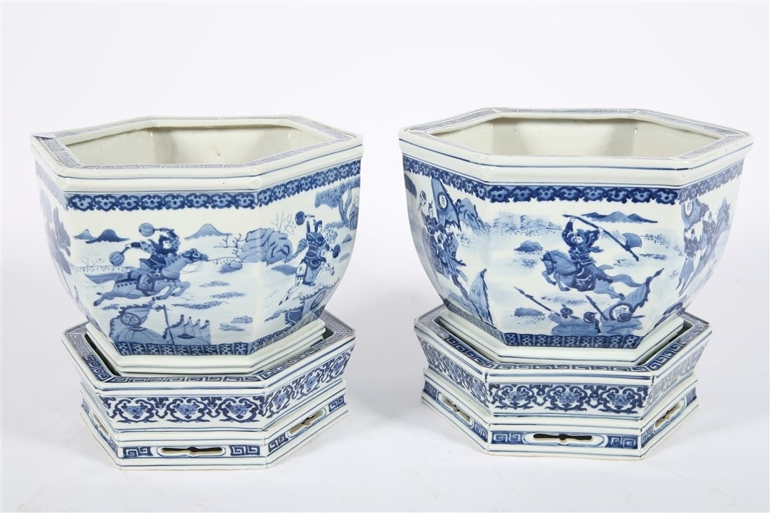 Pair of Hexagonal Blue and White Chinese Planters: Porcelain. Jardiniere: Height: 10", Length: 13", Depth: 12". Underplate: Height: 3 3/4", Length: 12", Depth: 10 3/4". Pair of matching jardinieres with hexagonal forms and warrior motif. Concentric ri