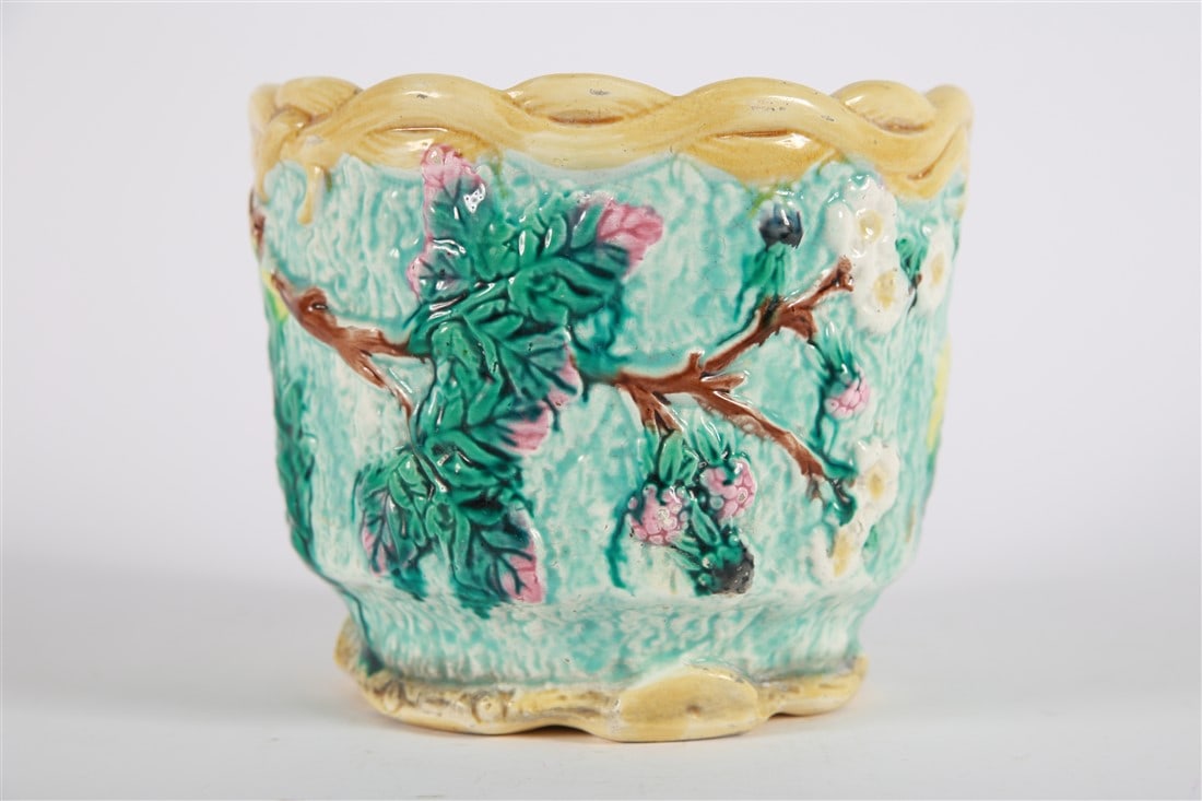 Majolica Blue Apple Blossom Planter: Glazed ceramic. Height: 6 1/4", Diameter: 7 1/4". Majolica planter depicting berries and apple blossoms. Blue, green, yellow, pink, and lavender glazes. Appears unmarked. Hole in the center of the bot