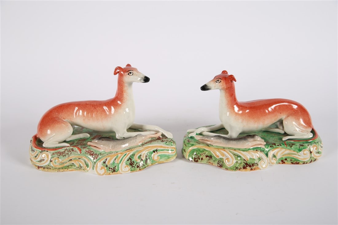 Two Staffordshire Greyhound Spill Vases: Ceramic, c. late 18th-early 19th century. Height: 6", Length: 10 5/8", Depth: 6" each. Pair of Staffordshire greyhound spill vases. Both depict the dogs with hunted hares. Both appear unmarked. Proven