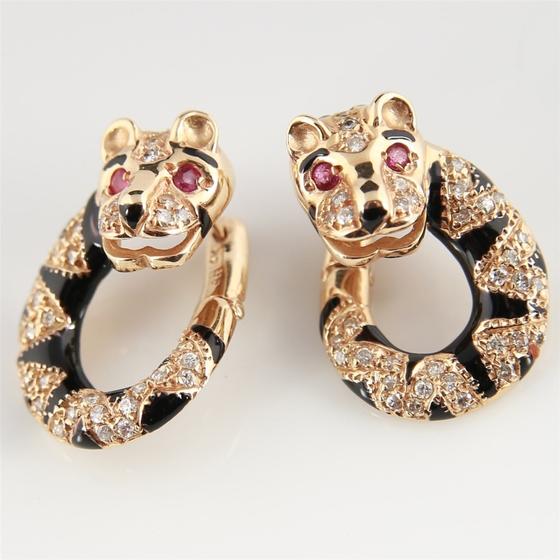 14k Yellow Gold, Enamel Tiger Earrings: Pair of 14k yellow gold tiger or leopard head earclip earrings with black enamel markings, diamond chips, and red gemstone eyes. Contains 72 round brilliant cut diamonds weighing approximately 0.60 ca