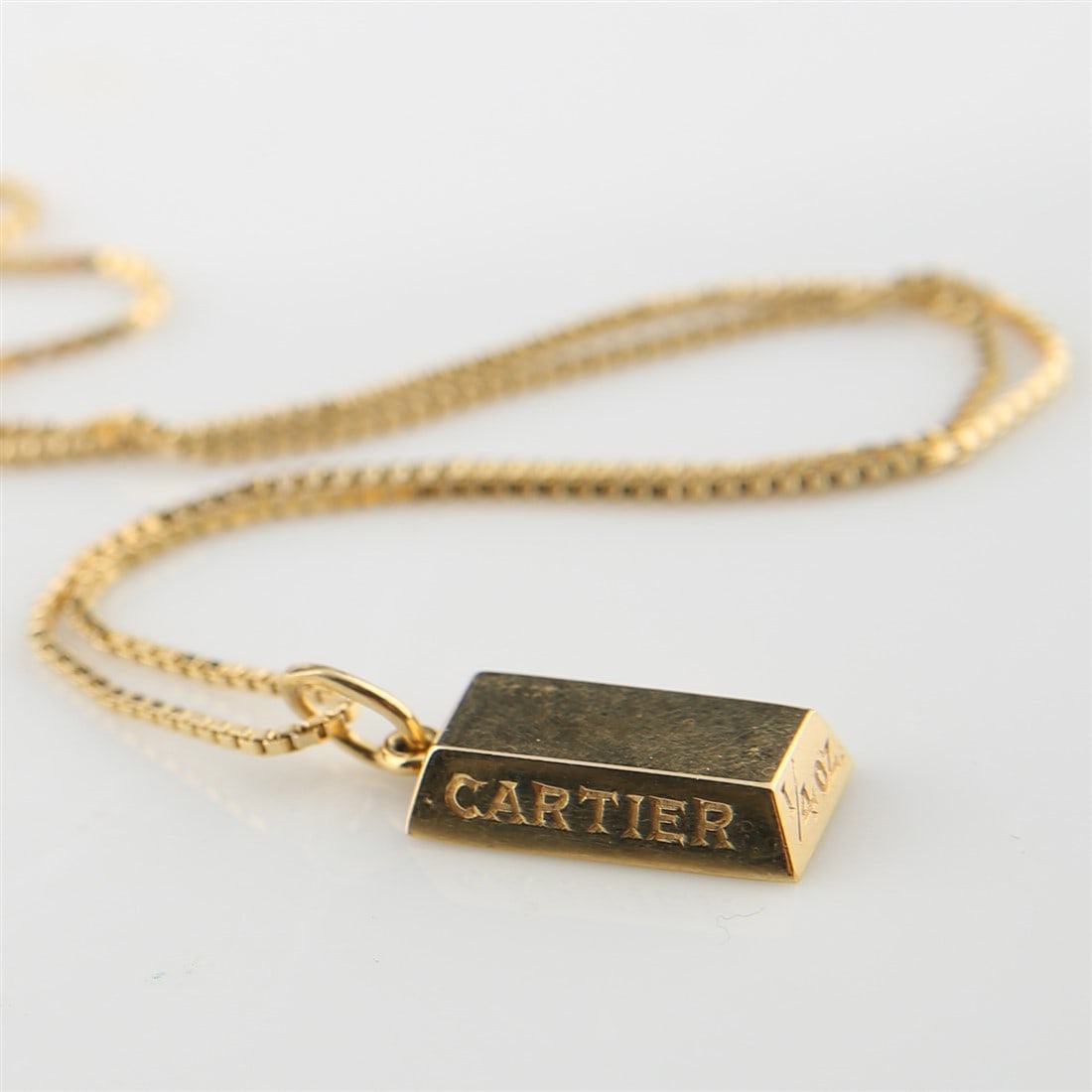Cartier, 18k Yellow Gold 1/4 Oz Bar Necklace: Cartier, 18k yellow gold bar pendant necklace with 14k yellow gold box chain. 18k yellow gold bar reads: "Cartier 18k" and "Cartier" on the side, as well as "1/4 OZ" on one of the sides. The necklace