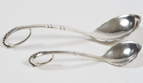 Two Gerog Jensen Sterling Serving Spoons, 2 Ozt.: Two Georg Jensen sterling silver serving spoons. Danish, 20th century. With curled and seed handles. Largest length 7". 2 troy ounces.