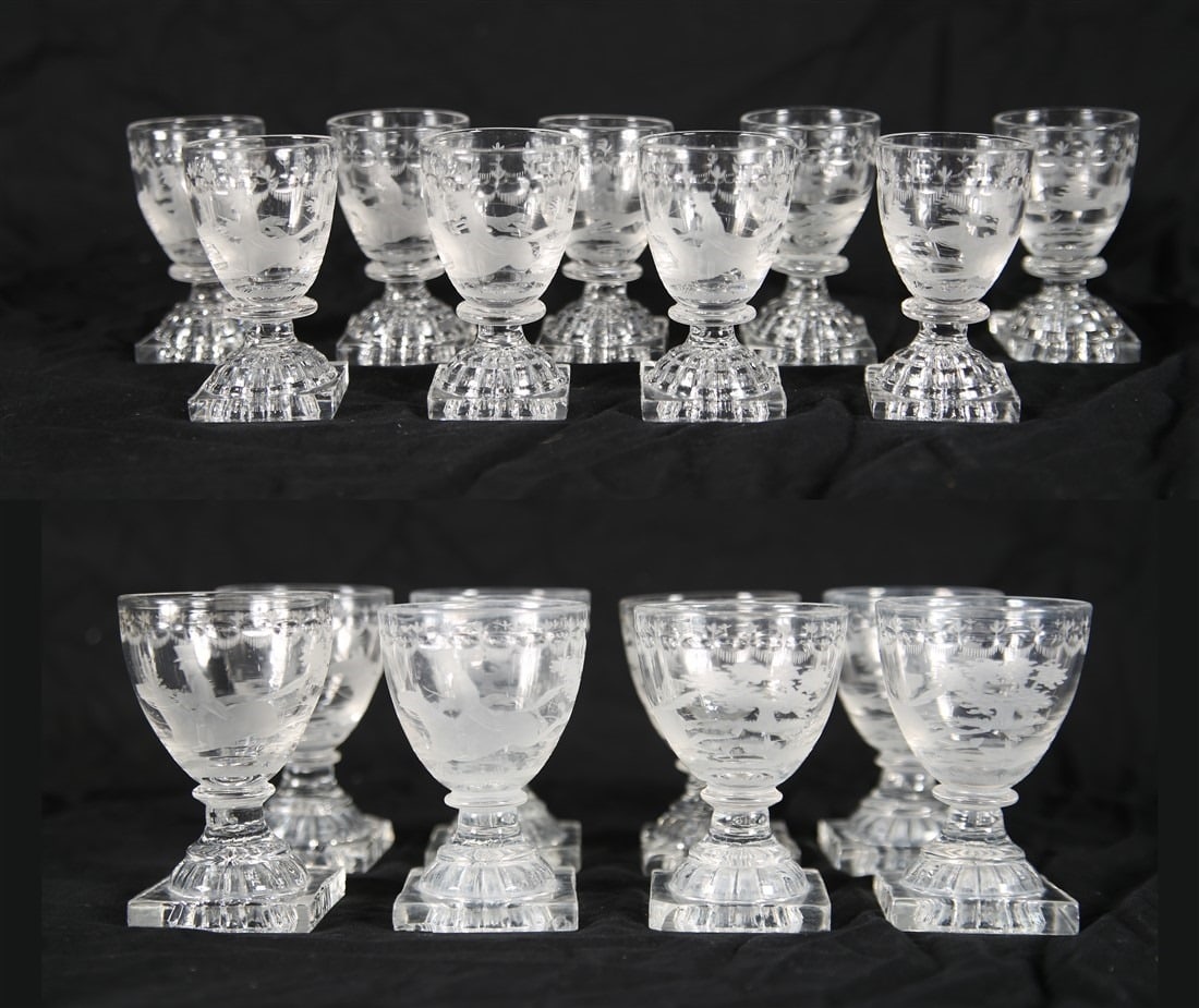 Set of Etched Fox Hunt Square Base Glasses: Glass. Taller: Height: 4", Diameter: 2 5/8". Shorter: Height: 3 1/4", Diameter: 1 3/4". Collection of etched glasses depicting a horseback fox hunt scene. Includes eight (8) taller glasses with square