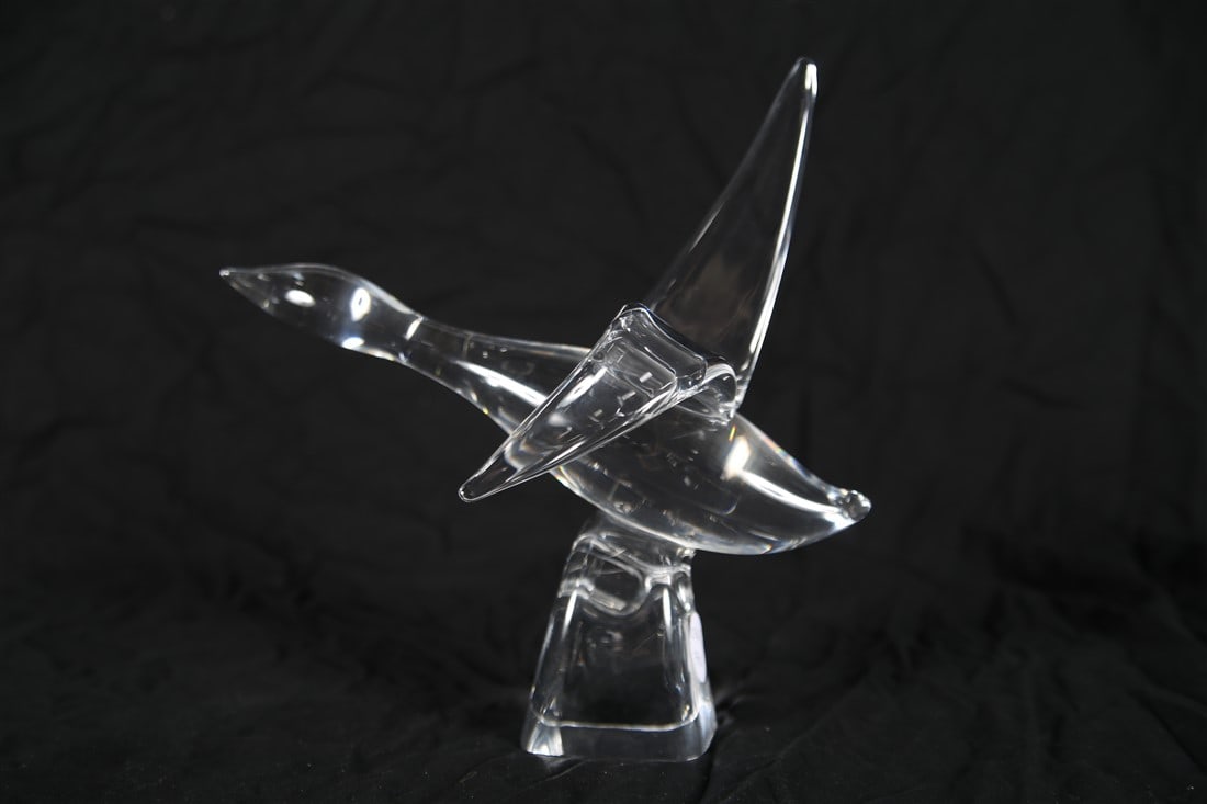 Steuben, "Canada Goose" Crystal Figure: Steuben Glass Works (American, established 1903). "Canada Goose". Crystal. Designed by Lloyd Atkins. Height: 10", Length: 10", Depth: 5". Crystal Canadian Goose in flight on a scrolled base. Etched si