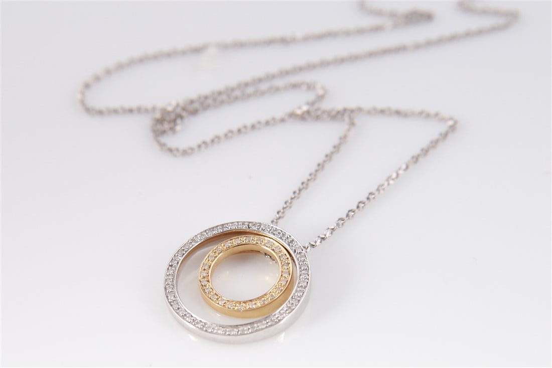 14k Yellow and White Gold Circle Diamond Necklace: 14k yellow and white gold necklace with double circle design. Circles lined with small diamond chips. Marked "14K" to the circles and to the clasp. Length: 18". Weight: 5.7g.