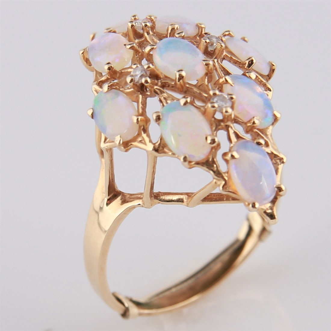 14k Yellow Gold Opal Diamond Ring: 14k yellow gold ring with diamonds and opals. Includes nine (9) oval opals and four (4) small diamonds. Marked "14K" to the interior of the band. Size: 9 with size guard. Weight: 5.5g.