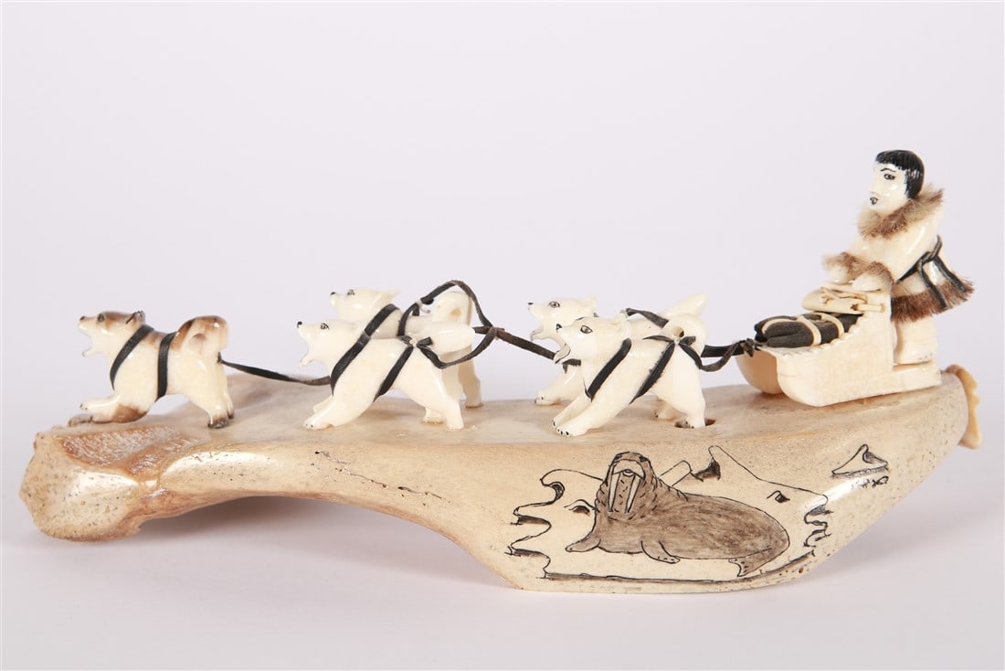 Mary Seppilu, Alaskan Carved Bone Dog Sled: Mary Seppilu (Native American, b. 1937). Carved bone. Height: 3 1/2", Length: 9 1/2". Carved bone Alaskan sled with sled dogs. Walrus painted on the side. Signed "Mary Seppilu Savoonga, Alaska".