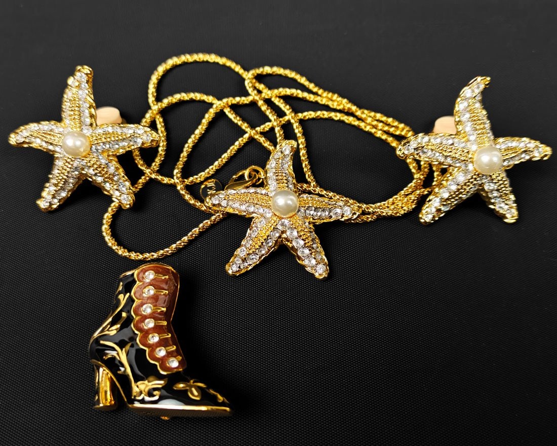 Kenneth J. Lane, Four Pieces of Fashion Jewelry: Kenneth J. Lane, four pieces of costume jewelry. Includes gold-tone necklace with sea-star pendant and matching clip-on earrings, and enamel boot pin / brooch.