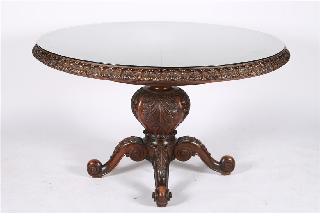 Pedestal Base Carved Wood Round Foyer Table: Carved wood, glass. Height: 30 1/2", Diameter: 52". Carved wood round foyer table with glass top. Pedestal base. Burled wood top.