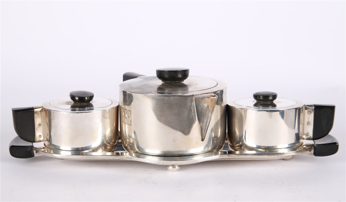 Wilcox Art Deco Silver Plated Tea Set: Wilcox. Silver plate, wood. Model 7037. Entire set: Height: 3 1/4", Length: 13", Depth: 7". Wilcox Art Deco silver plated tea set consisting of a central tea pot, creamer, and sugar bowl all assembled