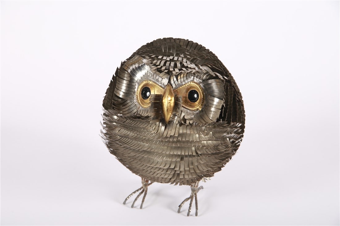 Sergio Bustamante, Cut Metal Owlet Sculpture: Sergio Bustamante (Mexican, b. 1949). Welded and cut brass and metal. Height: 9 1/4", Diameter: 7 1/2". Cut and welded metal sculpture in the shape of an owl or owlet. Black eyes. Each tuft is made of