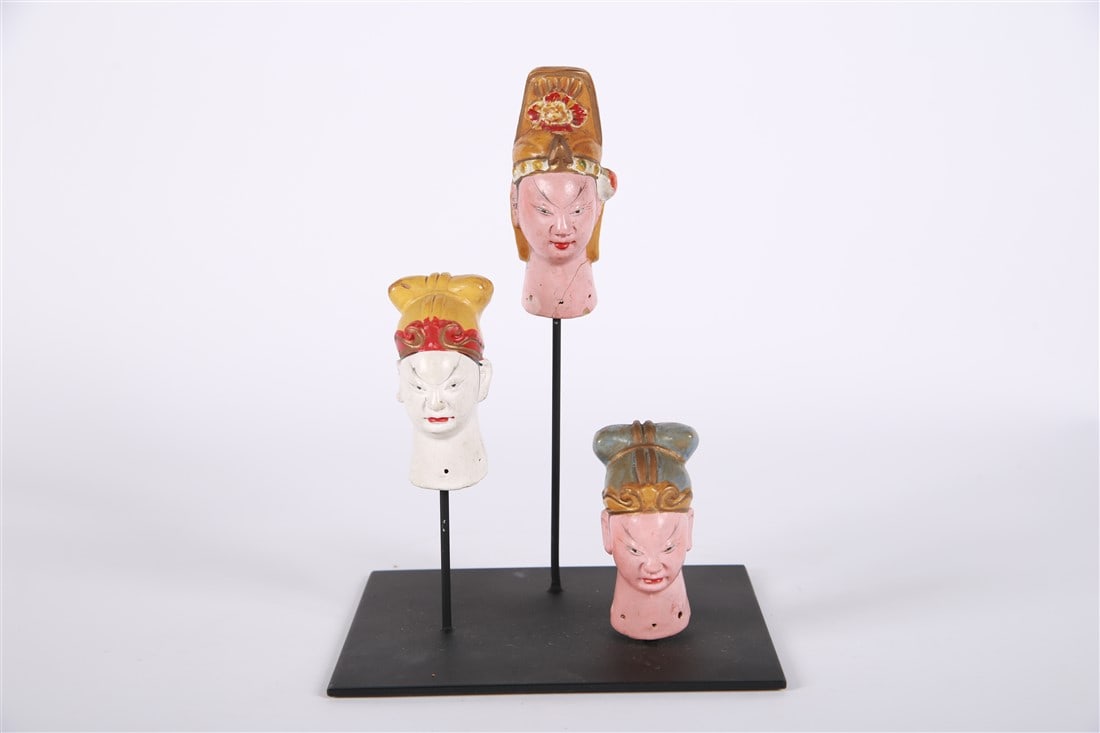 Collection of Mounted Puppet Heads: Painted ceramic. Height (of assembly): 8 1/2", Length: 6", Depth: 5 1/2". Collection of three mounted ceramic Chinese puppet heads. Removable from the base.