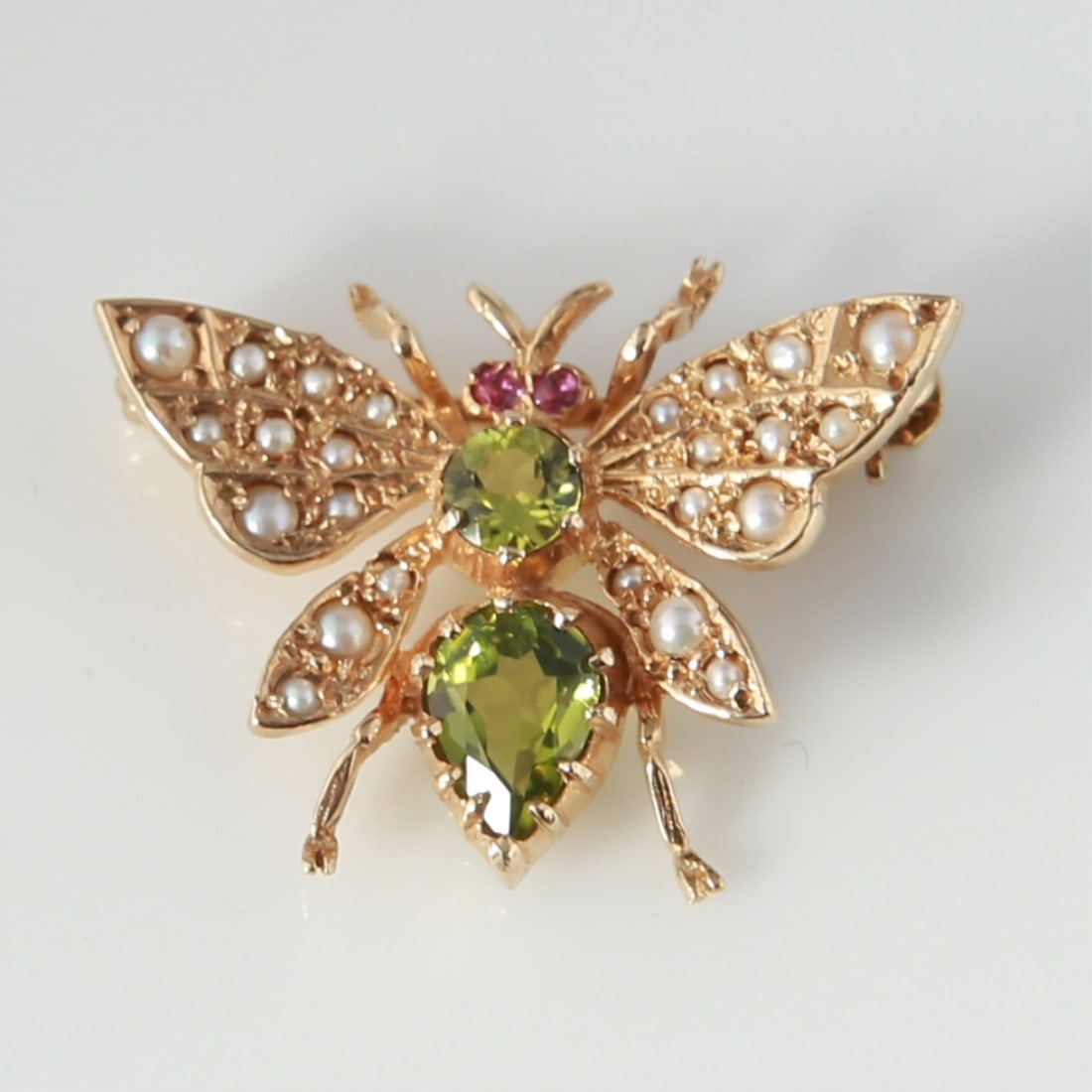9k Yellow Gold Butterfly Brooch: Peridot and seed pearl butterfly brooch made of 9 karat yellow gold. Brooch is set with (1) pear shape and (1) round cut peridot and (24) seed pearls. Brooch weighs a total of 3.8 grams. Peridots: