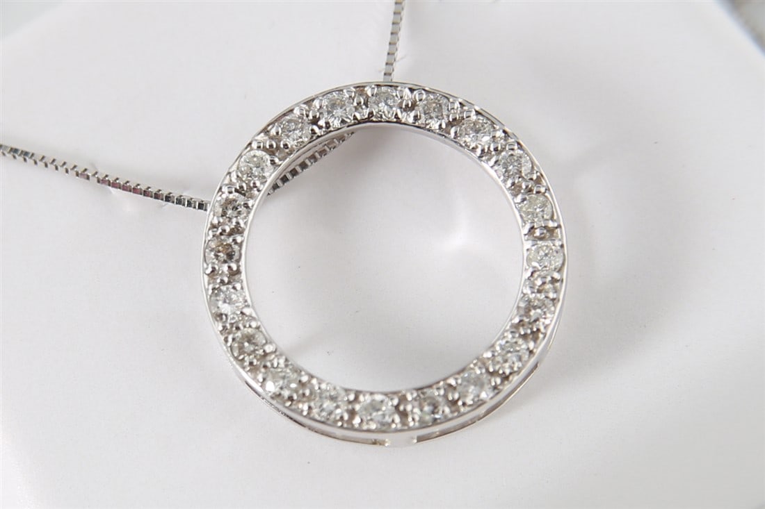 14k Diamond Open Circle Pendant Necklace: One diamond open circle pendant made of 14 karat white gold. Pendant is set with (20) round brilliant cut diamonds and is suspended from a 14 karat white gold box link chain measuring 18 inches long.
