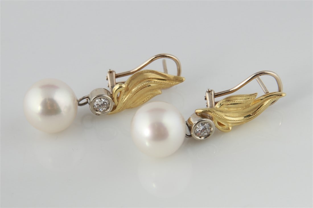 14k Yellow Gold Diamond Pearl Earrings: One pair of pearl and diamond leaf motif dangle earrings made of 14 karat gold. Earrings are each set with (1) round South Sea pearl dangling from a brushed leaf design in yellow gold. Accented with (