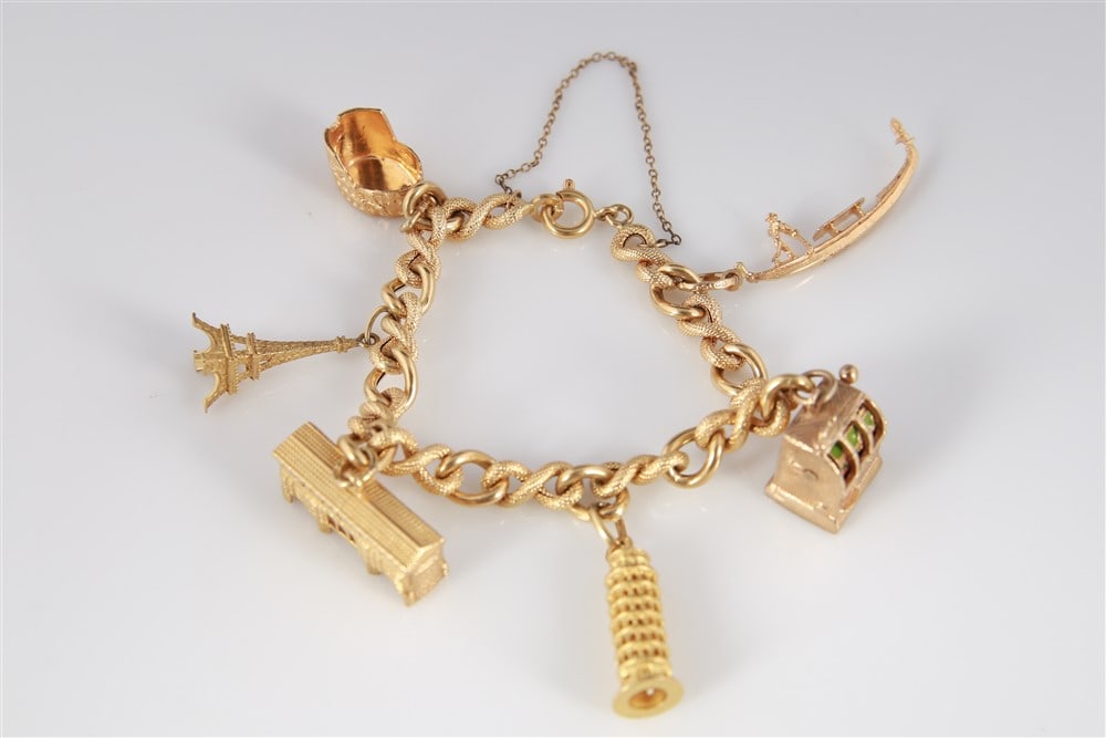 18k Yellow Gold Bracelet with Six Charms: Length: 7". Weight: 34 grams. 18k yellow gold bracelet with six gold charms. Bracelet has a spring ring clasp and safety chain. Charms include 18k Eiffel Tower, 18k Colosseum, 18k Leaning Tower of Pis
