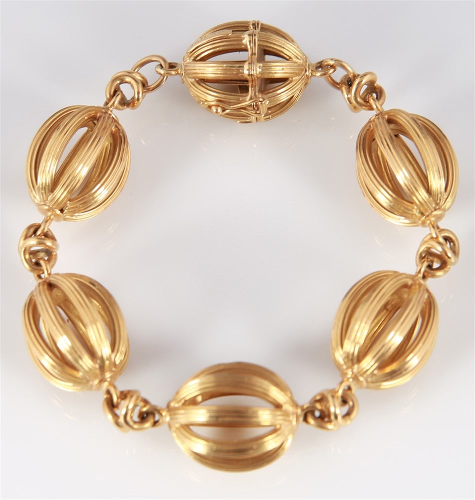 18k Yellow Gold Lady's Oval Bead Bracelet: 18k yellow gold lady's bracelet. Six oval shaped hollow caged style beads at approx. 17.5mm x 20.0mm each. One bead is a hidden box clasp with safety. Total weight: 47.5g.