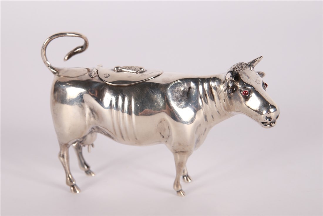 Dutch Silver Cow Creamer: Silver. Height: 3 1/4", Length: 5", Depth: 1 1/2". Total weighable: 2.825 ozt. Figural creamer in the shape of a cow with red glass eyes and a flip lid on back. The curly tail serves as handle. Bottom
