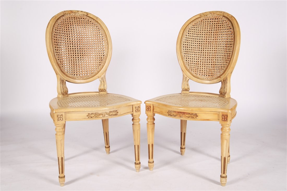 Pair of Louis XVI Style Balloon Back Caned Chairs: Wood, cane. Height: 36 1/2", Length: 19", Depth: 16 1/2". Matching pair of caned Louis XVI style chairs with balloon backs, cream paint, and gilt decoration. Marked "Made in Italy" at underside.
