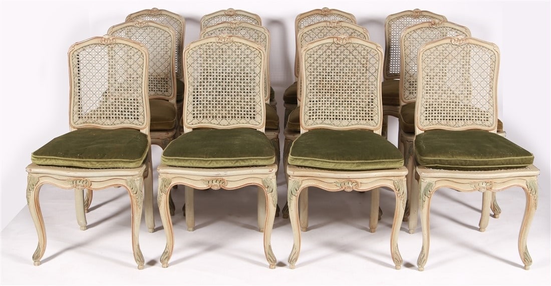 Twelve French Provincial Style Dining Chairs: Wood, cane, velvet. Height: 35 1/2", Length: 19", Depth: 16 3/4". Matching set of twelve caned French Provincial style dining chairs. Green paint with pink accents and green velvet seat cushions.