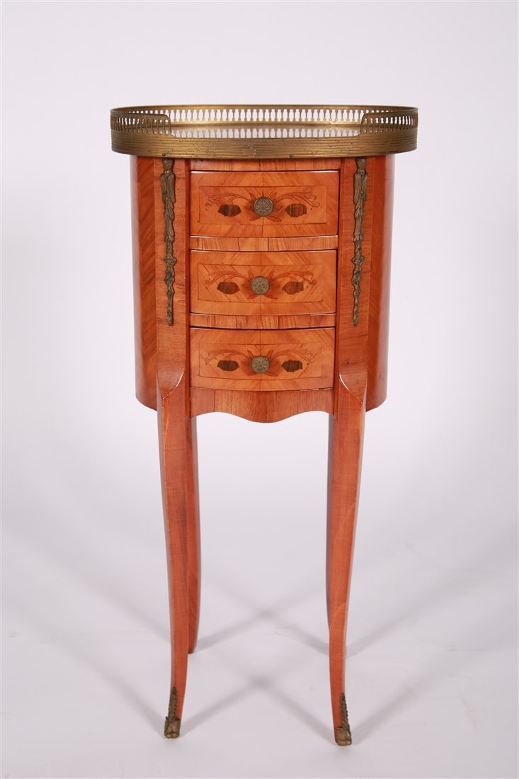 Louis XV Style Side Table: Wood, brass. Height: 29 1/2", Length: 13 1/2", Depth: 10 3/8". Louis XV style side table. It features three drawers with marquetry inlay, cabriole legs with brass ormolu mounts, and a marble top