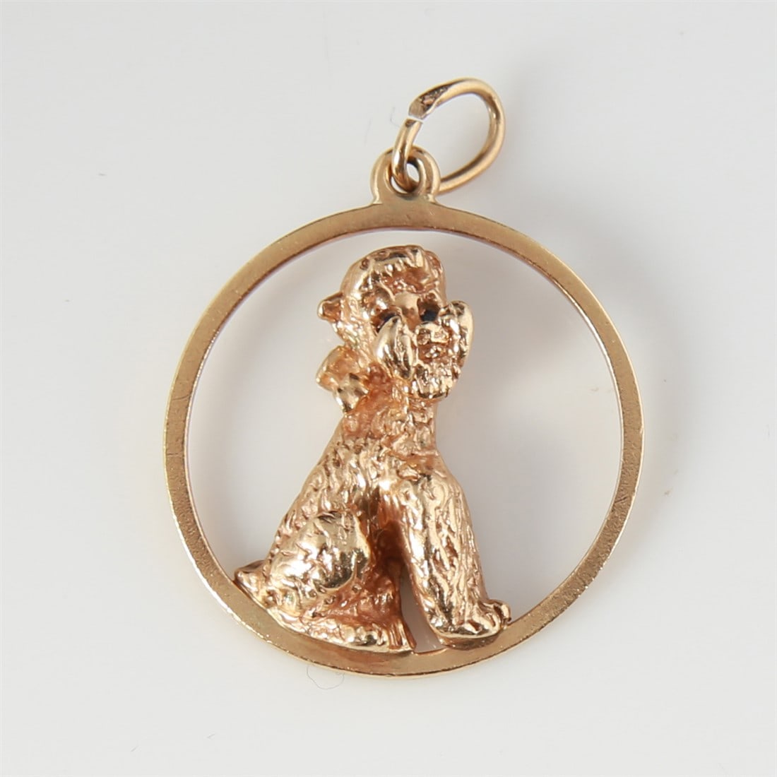 14k Yellow Gold Dog Charm with Sapphires: 14k yellow gold, sapphires. Diameter: 1". Weight: 7g. 14k yellow gold charm depicting a seated dog within a hoop with two sapphire eyes. Marked 14K to the reverse.