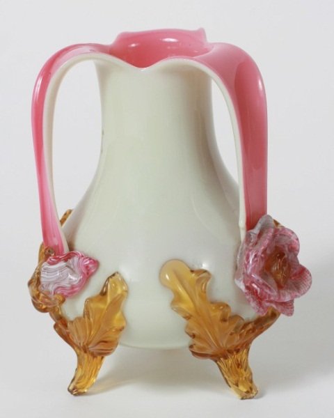 White Cased Pink Glass Vase, American, 20th C.: White cased pink glass vase. American, 20th century. With three arched handles terminating in floral blossoms and leaves. Height 7 1/2".