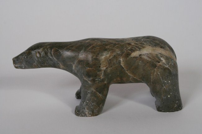 Inuit Carved Stone Polar Bear, 20th C.: Inuit carved soapstone polar bear. 20th century. Labeled "E5-57" on bottom of front right paw with illegible markings on bottom of front left paw. Height 3", length 7".