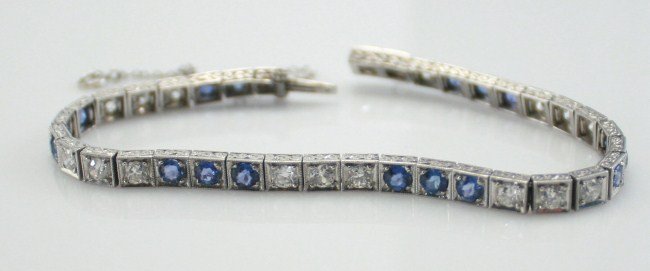 Platinum Bracelet with Diamonds and Sapphires: Platinum bracelet with diamonds and sapphires. 20th century. Square platinum links with scroll motif engraved edges, each link set with a diamond or sapphire. With safety chain. Having 18 diamonds, 1.