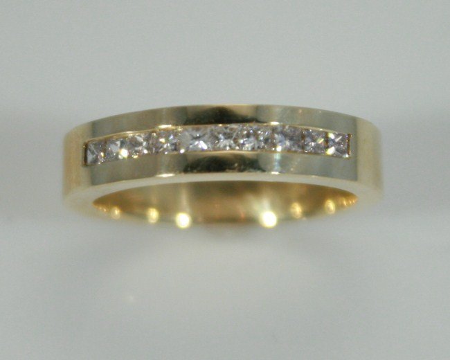14K Gold Band with Channel Set Diamonds: 14 karat yellow gold band with channel set diamonds. 20th century. Set with 10 princess cut diamonds, 0.5 ct. total weight. Ring size 6 1/2. 14 karat gold weight 5.4 grams. Condition: Appears fine.