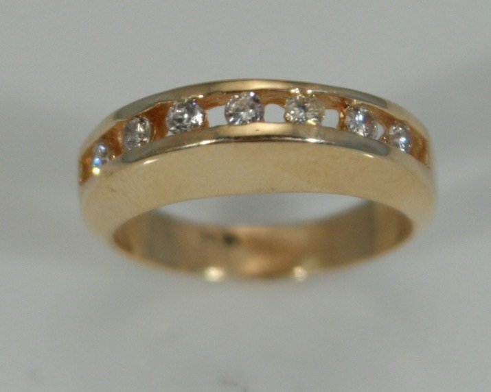 14K Gold and Diamond Band: 14 karat yellow gold and diamond band. 20th century. Band set with seven wide channel set diamonds, 0.21 ct. total weight. Ring size 5 1/2. 14 karat gold weight 4.7 grams. Condition: Appears fine.
