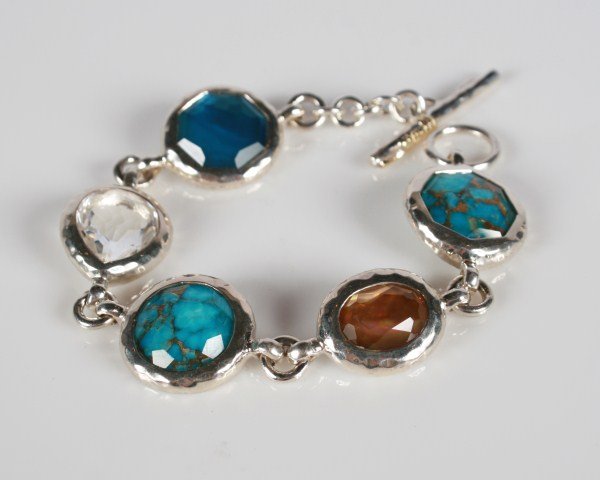 Ippolita Bracelet: Ippolita sterling silver bracelet with semiprecious stones. 20th century. Hammered sterling silver bracelet set with turquoise, mother-of-pearl, clear crystal, and aqua quartz doublets backed by mothe