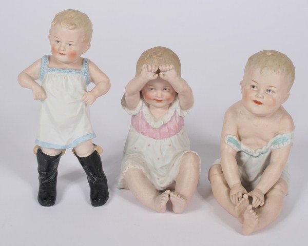 Group of Three German Bisque Piano Babies: Group of three German bisque piano babies. The standing piano baby titled "Walking in Father's Shoes," numbered "107" to base, and is probably made by Heubach. The seated babies are both numbered to b