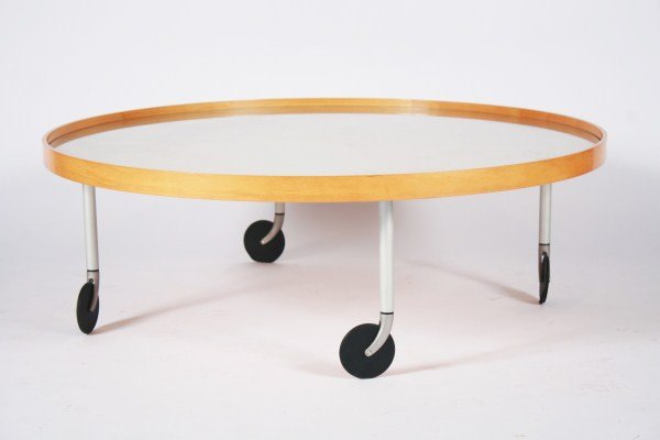 Ligne Roset Rolling Occasional Table: Contemporary Ligne Roset rolling occasional table. 21st century. Round occasional table having a wood frame and glass top raised on metal legs ending in large casters. Unmarked. Height 13 3/8", diamet