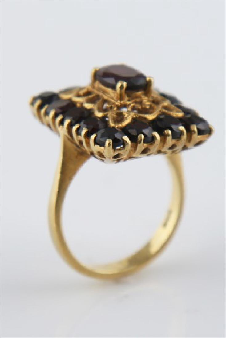 Ladies 18k Yellow Gold Garnet Ring: One ladies garnet ring made of 18k yellow gold. Ring is set with one (1) oval cut garnet and fourteen (14) round cut garnets, all prong set. Piece is a size 7 1/2 and weighs 9.7 grams.