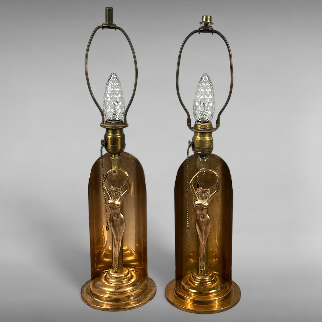 Pair of Vintage Art Deco Brass Nude Female Figure Boudoir Lamps: • This striking pair of vintage boudoir lamps exemplifies Art Deco style • Cylindrical brass bodies with open sides reveal finely sculpted nude female figures in expressive poses • Flam