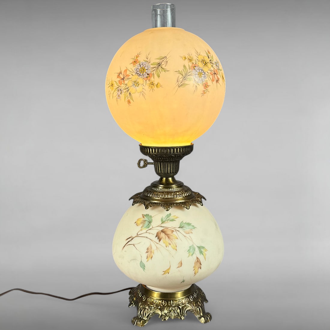 Vintage Hand-Painted Milk Glass Converted Oil Lamp with Floral and Leaf Design: Vintage Hand-Painted Milk Glass Converted Oil Lamp with Floral and Leaf Design Victorian Style • Dual Spherical Shades • Ornate Brass Base This converted oil lamp features two spherical milk