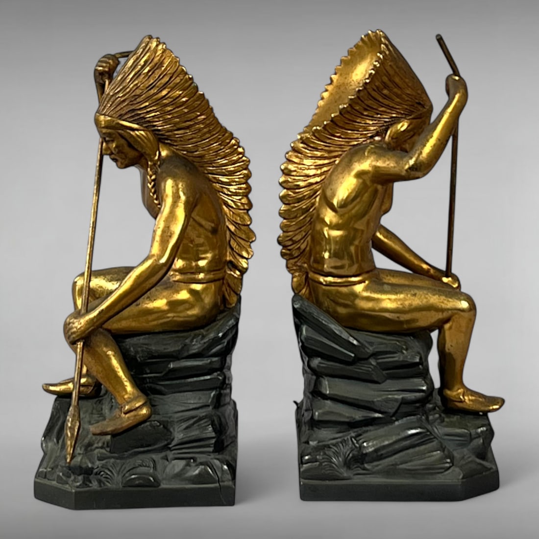 Early 20th-Century Gilded Bronze-Clad Bookends — Seated Native American Warriors: Early 20th-Century Gilded Bronze-Clad Bookends — Seated Native American Warriors Machine Age Sculpture • Spear & Headdress Motif • Gilded Spelter Metal This pair of vintage bookends, produ