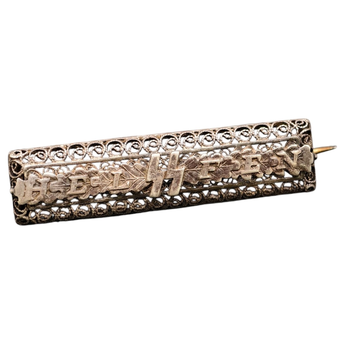 Third Reich Nazi SS Helfen Ladies Brooch: This women's SS Helfen brooch from the Second World War is a distinctive and refined piece, featuring an original SS Helfen badge mounted onto a personalised openwork filigree backing in what appears 