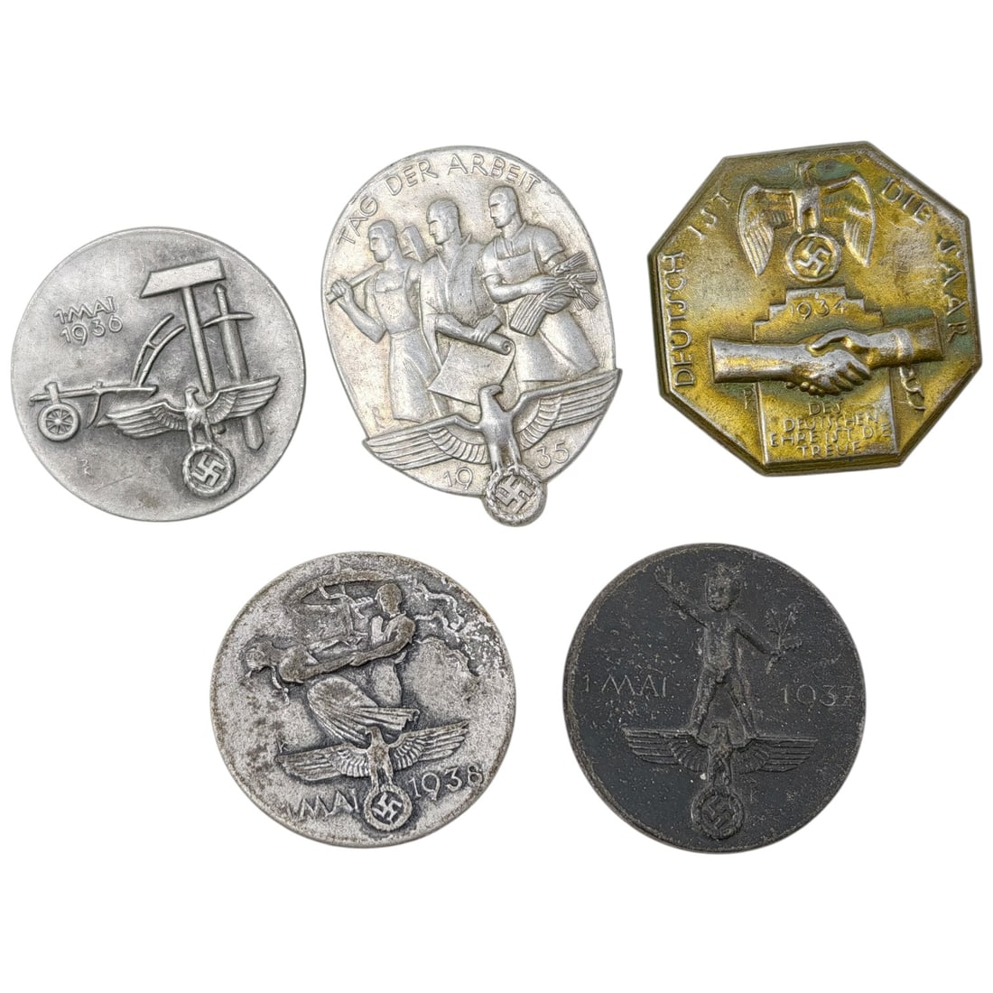 Third Reich Nazi Set of Tinnie Badges: A set of German commemorative tinnie badges issued for May Day (1. Mai / Tag der Arbeit) celebrations, dated 1935, 1936, 1937, and 1938. Designs include workers with tools, a horse-drawn plow, a child