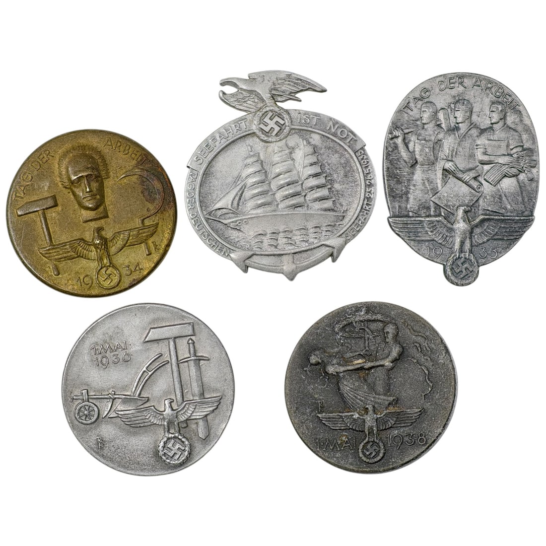 Third Reich Nazi Set of Tinnie Badges: A set of German tinnie badges commemorating May Day (Tag der Arbeit / 1. Mai) and related worker/maritime themes, dated 1934, 1935, 1936, and 1938. Designs include a worker's head with hammer and swas